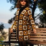 Kadın model motif uzun hırka ile poz veriyor, gün batış saatleri güneşli